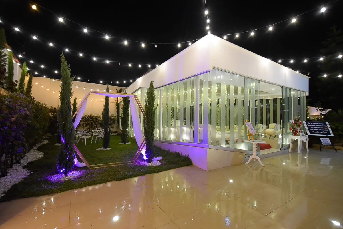 Exterior nocturno de Hacienda Común y Silvestre con jardines iluminados