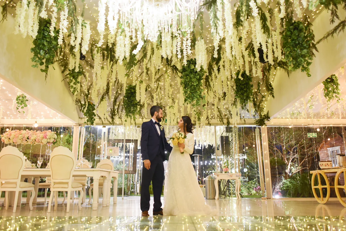 Pareja bajo flores colgantes en el salon de Casa Josue Guaymaral
